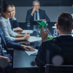 Late at Night In the Corporate Office Meeting Room: At Conference Table Executive Director Talks to a Board of Directors, Investors and Business Associates. Over the Shoulder Shot.